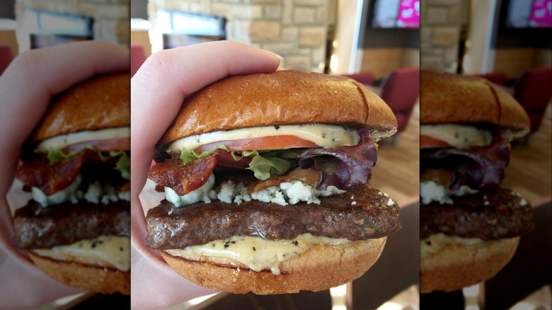 Hand holding Wendy's bacon and blue burger
