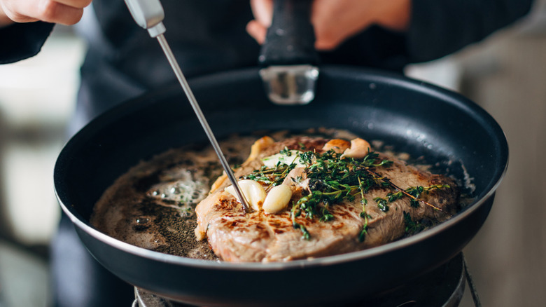 Measuring temperature of meat in skillet
