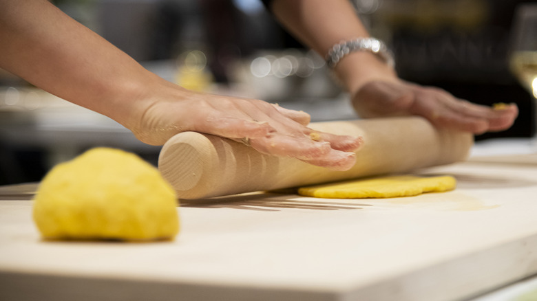 person rolling pasta dough