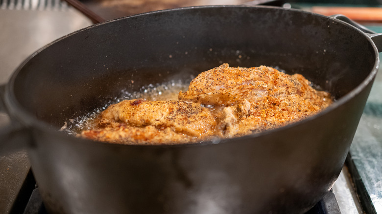 Frying chicken in large black cast iron pot