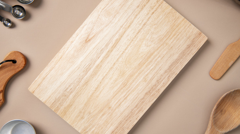 Light wooden cutting board on beige surface