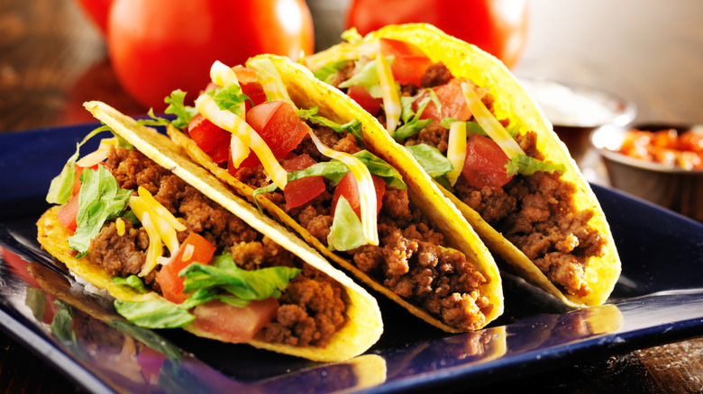 Crunchy tacos filled with ground meat, tomato, lettuce, and cheese