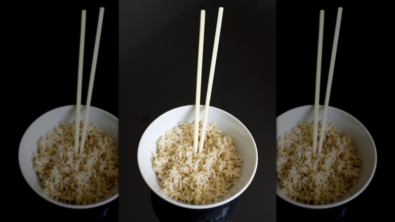 a bowl of rice with chopsticks stuck upright