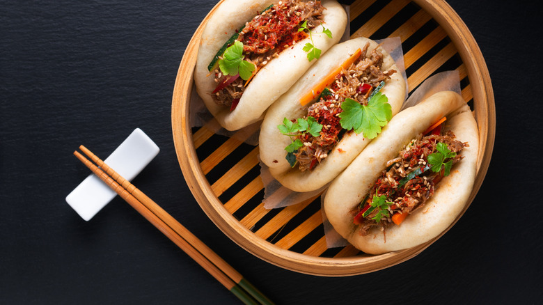 a basket of steamed bao next to chopsticks