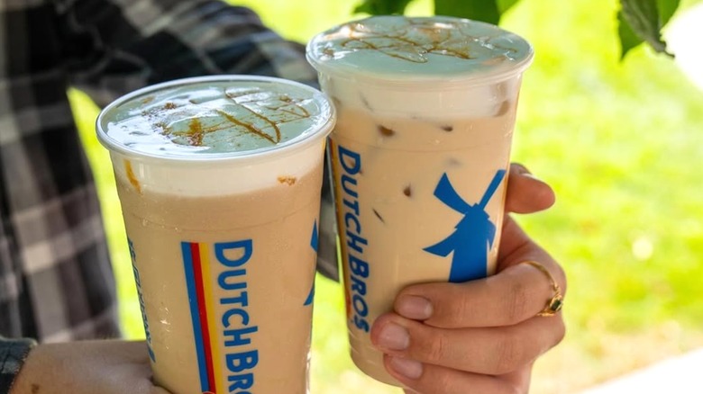 Person holding two Caramel Pumpkin Brûlée Lattes from Dutch Bros