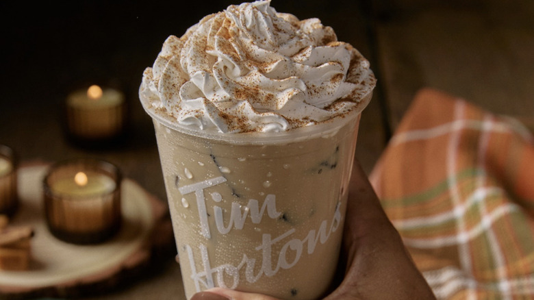 Hand holding iced Tim Hortons Cinnamon Caramel Apple Latte