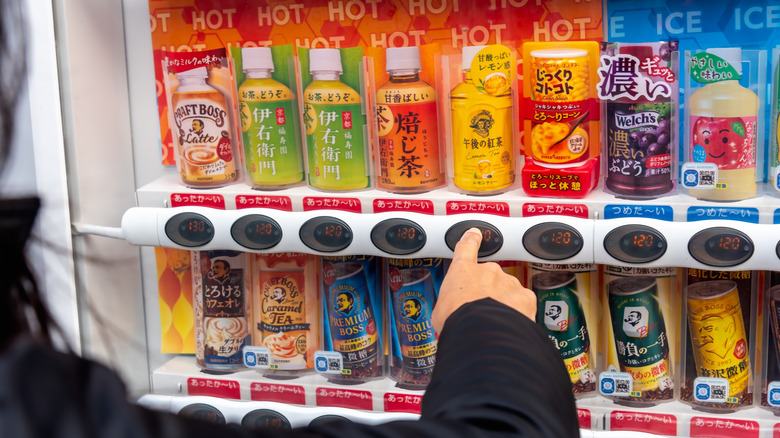 Hand selecting product from colorful vending machine