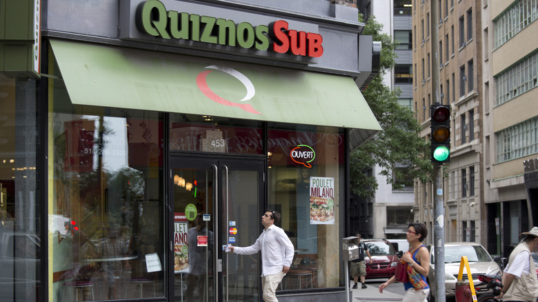 Person walking into Quiznos location in city