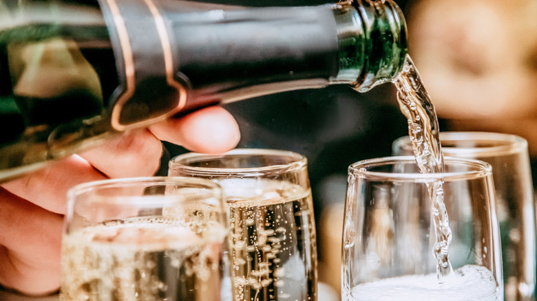 Close up of Champagne bottle pouring into glasses.