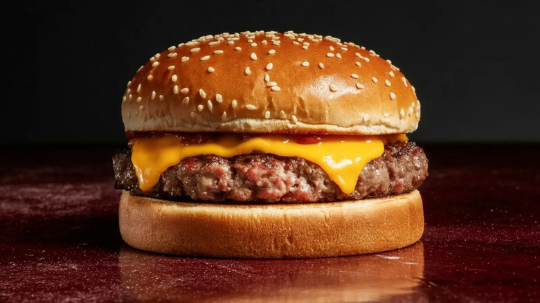 close-up of cheeseburger with sesame seed bun on table with dark background