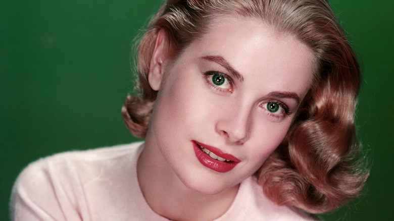 Grace Kelly in pink cardigan against green background.