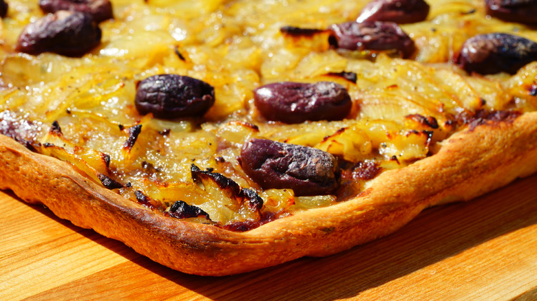 Close-up of the corner of a pissaladiére tart with onions and black olives.