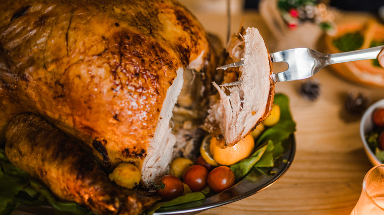 Close up of turkey with sliced meat on serving fork.