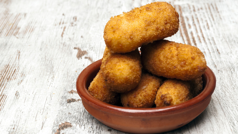 croquettes stacked in brown dish on rustic table