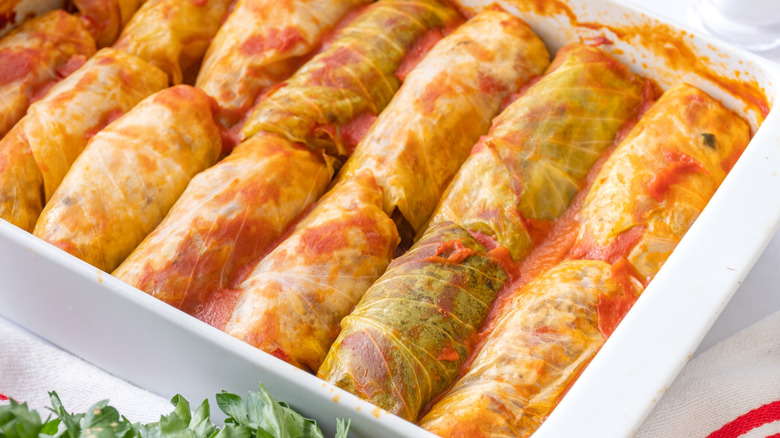 Stuffed cabbage rolls and tomato sauce in white baking dish