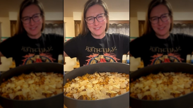 Person holding dish of ground beef macaroni casserole, topped with crushed potato chips