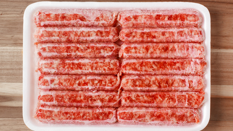 Package of frozen breakfast sausages with freezer burn on wooden surface