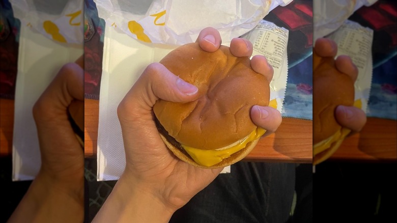 hand gripping McDonald's burger over packaging, mirrored image
