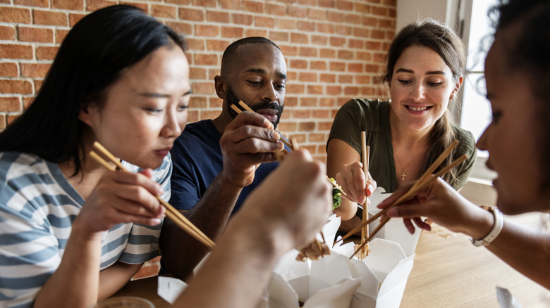 Group digging in on takeout with chopsticks