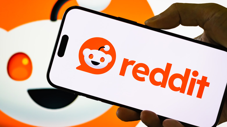 Reddit app on phone with Reddit logo in background