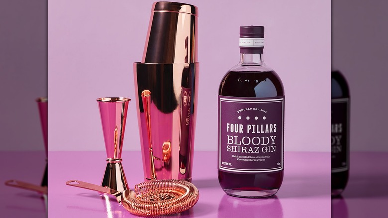 Four Pillars Bloody Shiraz gin and bar tools on a purple glass counter