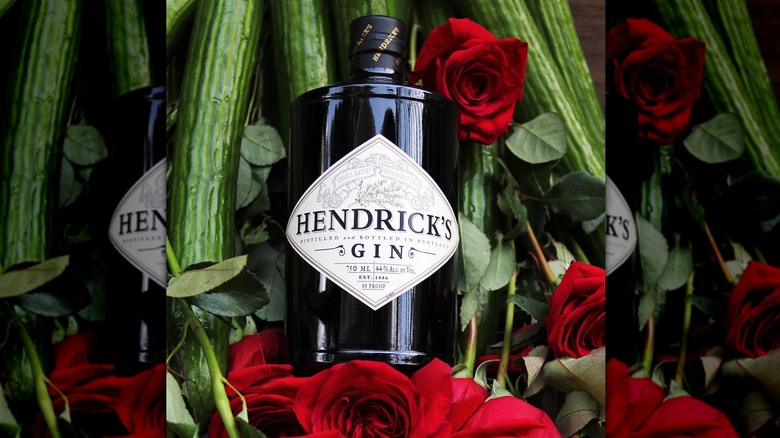 Hendrick's gin bottle with roses, greenery, and cucumbers in the background