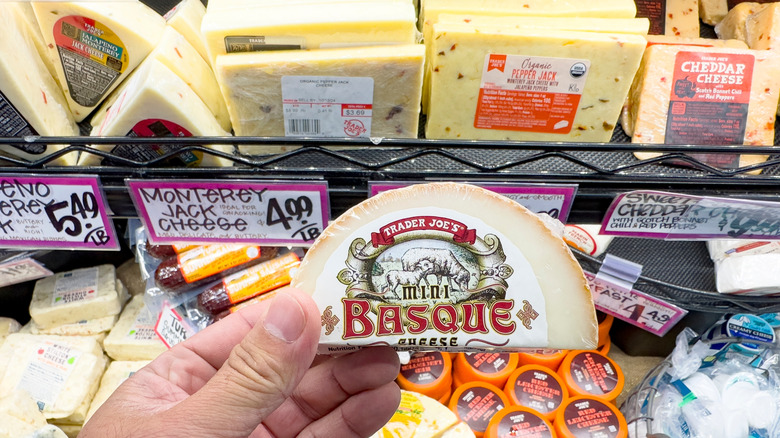 Person holding block of Mini Basque cheese in grocery store cheese aisle