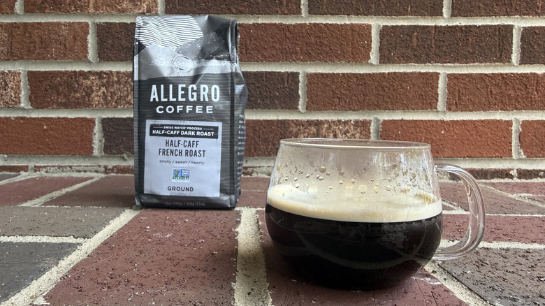 Bag of half-caff ground coffee with simple packaging, standing in front of brick wall