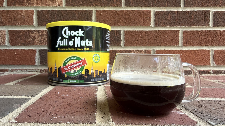 Cylindrical canister of half-caff ground coffee with NYC city skyline on packaging, set against brick wall