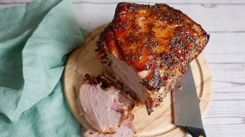 Sliced glazed ham on wooden cutting board with knife