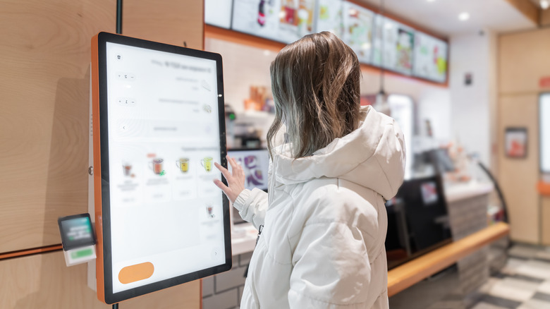 Woman interacts with a digital kiosk in a fast food restaurant