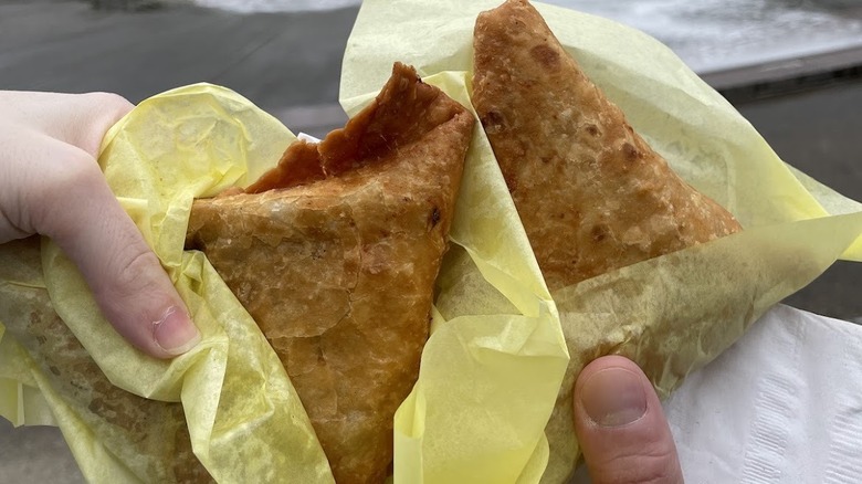 Sambusas in yellow paper held by two hands