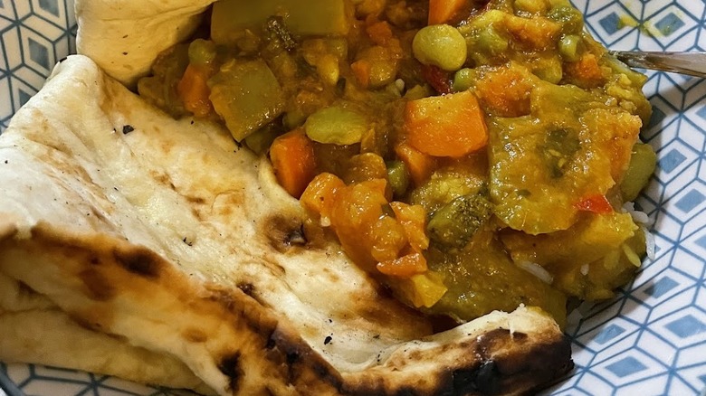 Coconut curry with naan in a blue bowl