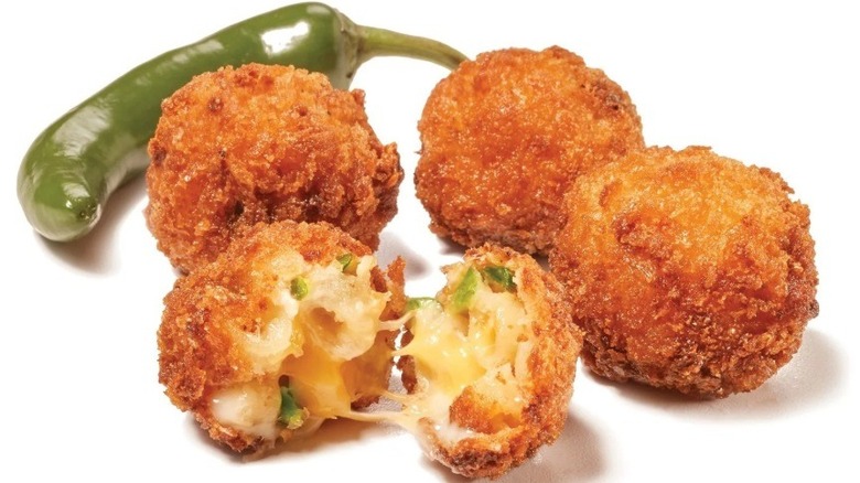 One jalapeño and four mac and cheese bites, one split open to show gooey interior