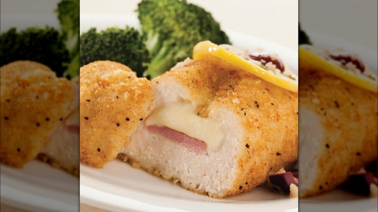 Broccoli and stuffed chicken breast sliced open to show interior on plate