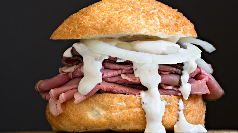 baltimore pit beef sandwich with beef tiger sauce raw white onion in a kaiser roll