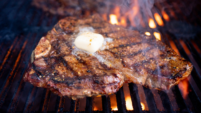 t-bone steak on a fired up grill with a dollop of butter