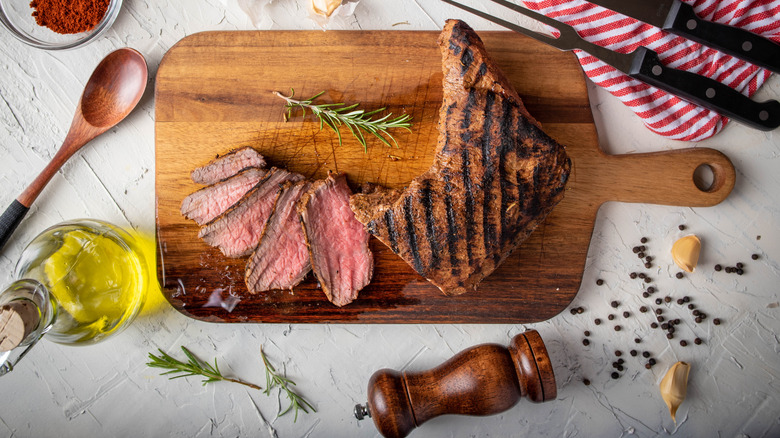 santa maria style tri-tip sliced on a wooden board with marinade ingredients around it