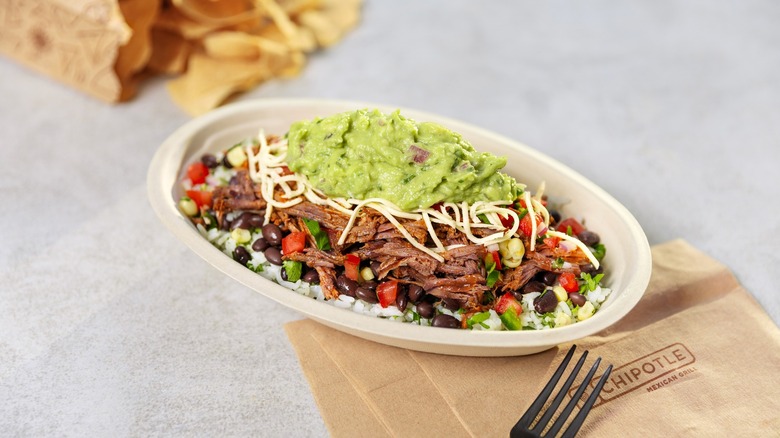 Chipotle burrito bowl with napkin and chips in background