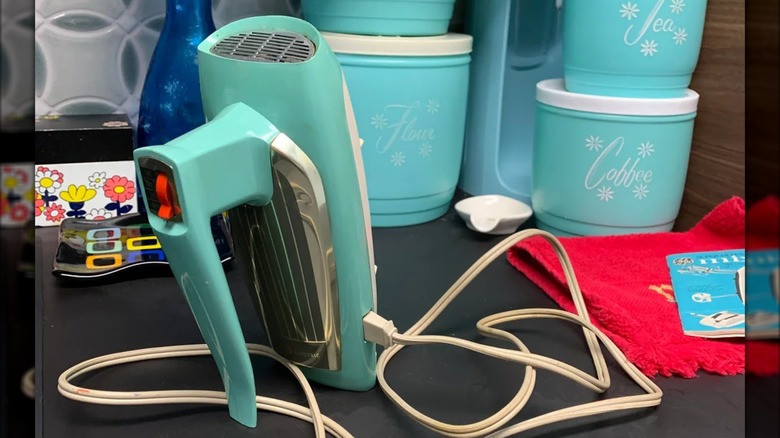 Light blue vintage hand mixer and knife sharpener combo on countertop