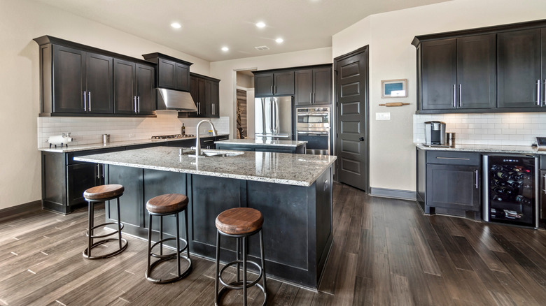 A kitchen with dark wood cabinets, granite countertops, and a wood floor