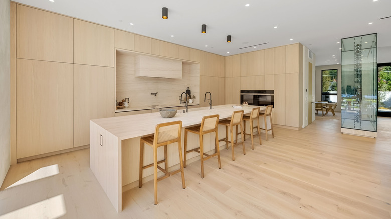 A bright kitchen with light wooden fixtures and gold hardware