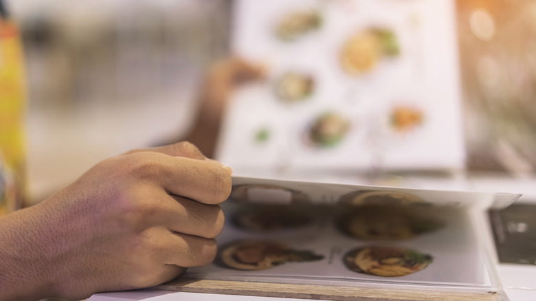 Close-up of male hand flipping pages of a restaurant menu