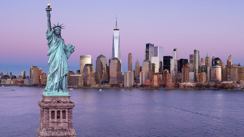 NYC skyline with statue of liberty at dusk