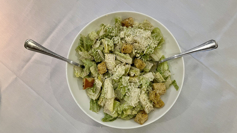 Caesar salad with two spoons, croutons, and parmesan cheese