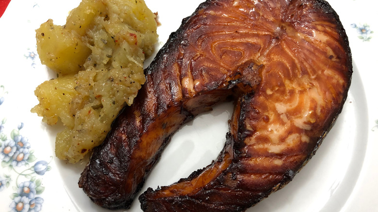 Overcooked salmon on white plate with side dish