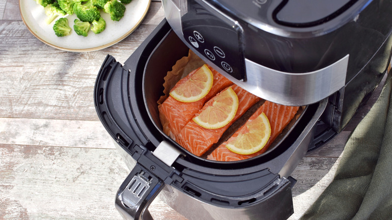 Raw salmon with lemon slices peeking out of air fryer