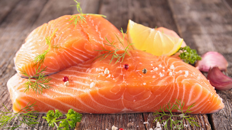 Raw salmon fillets with lemon wedge and herbs