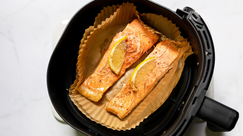 Cooked salmon in air fryer basket with air fryer liner
