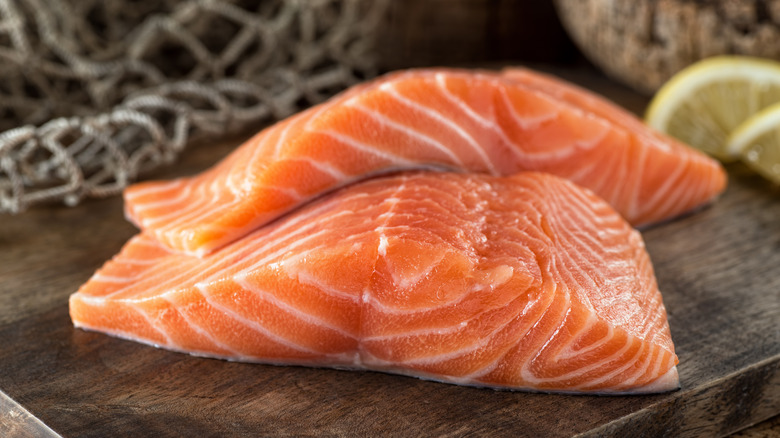 Two raw salmon fillets on wooden cutting board